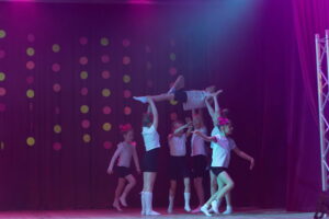 mākslas vingrotāju priekšnesums. Viena meitene pacelta gaisā.